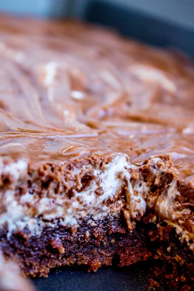 a close up shot of Mississippi mud cake showing layers of chocolate cake, marshmallow creme, and chocolate frosting. 