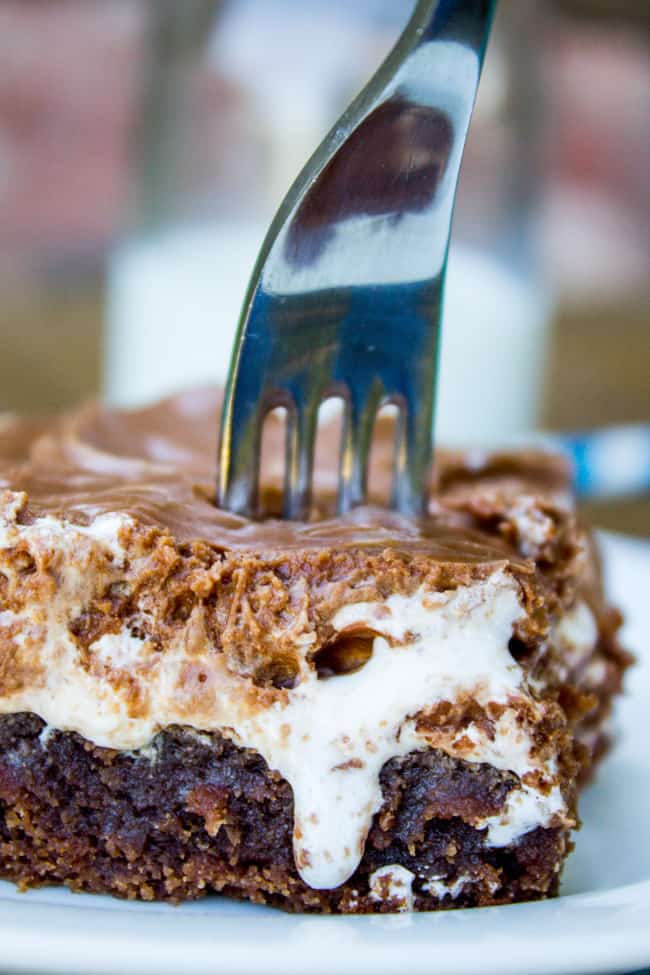 a fork stuck into a slice of Mississippi mud cake with marshmallow creme dripping down the side. 
