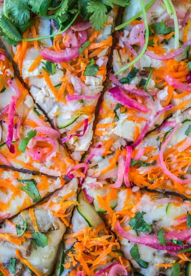 a sliced pizza with carrots, zucchini, pickled red onions, cilantro, and cheese.