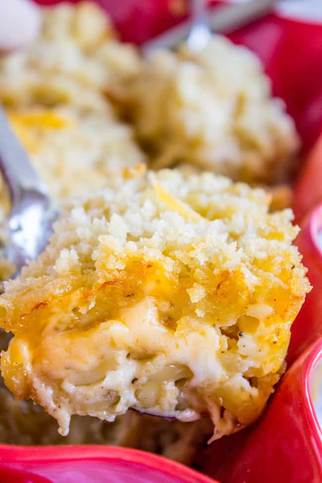 scooping baked mac and cheese from a baking dish.