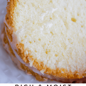 A close-up of a thick slice of golden, moist dessert cream cheese pound cake with a light glaze. Text reads: Rich & Moist Cream Cheese Pound Cake. The Food Charlatan.