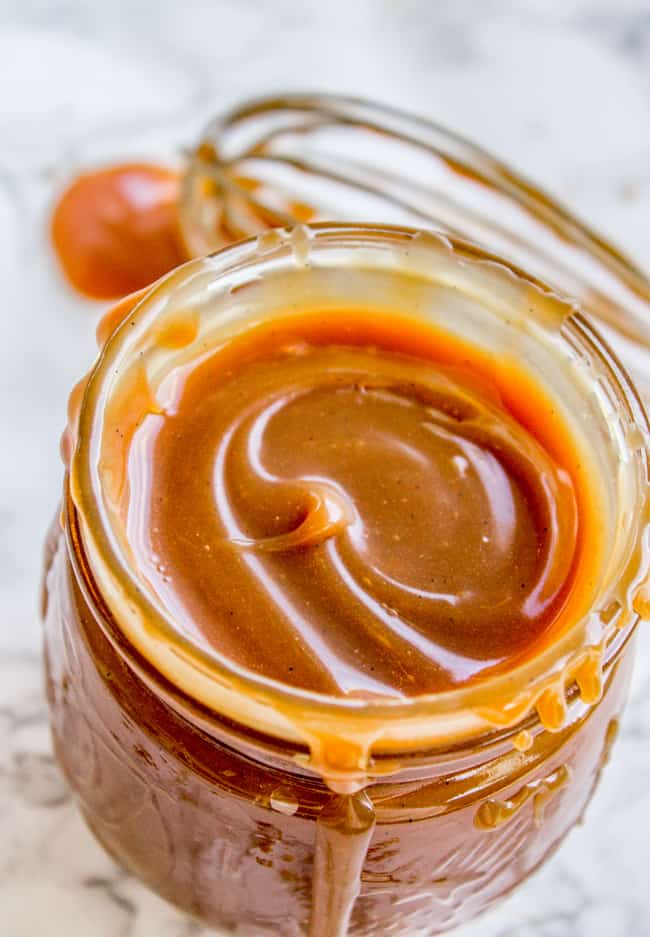 a mason jar of homemade caramel sauce with a whisk in the background.