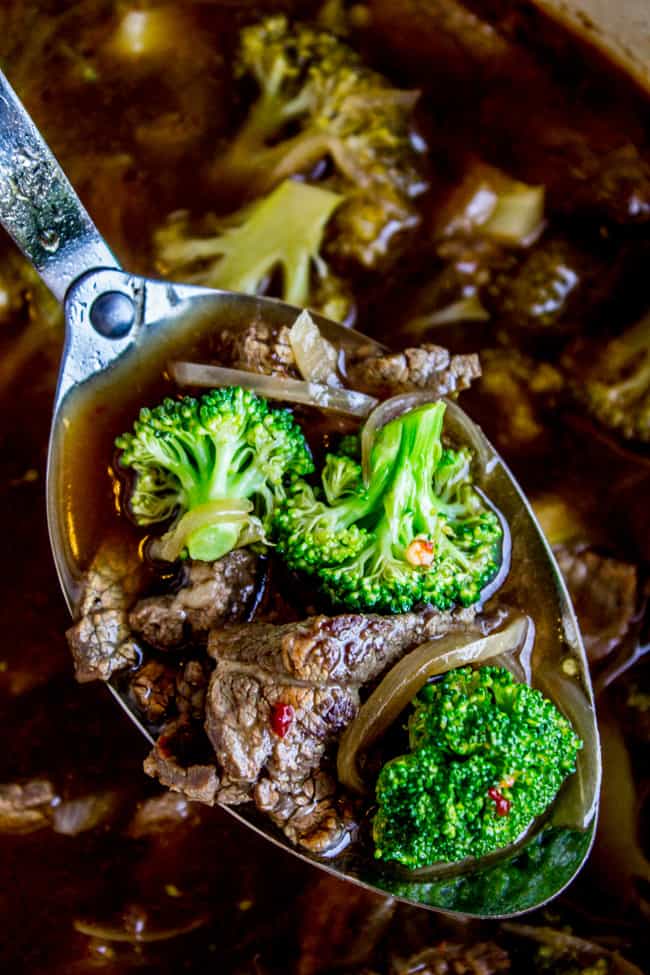 a metal spoon lifting beef and broccoli soup.