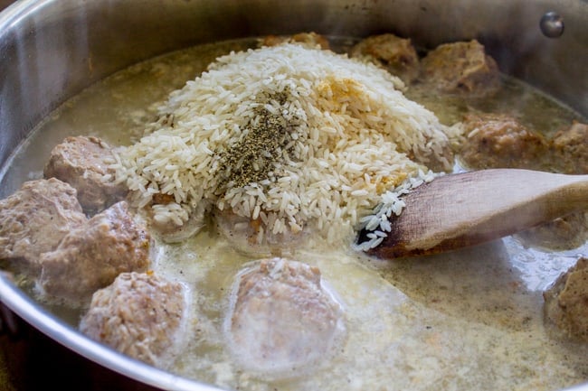 mixing rice, beef broth, seasonings, and meatballs in a skillet.