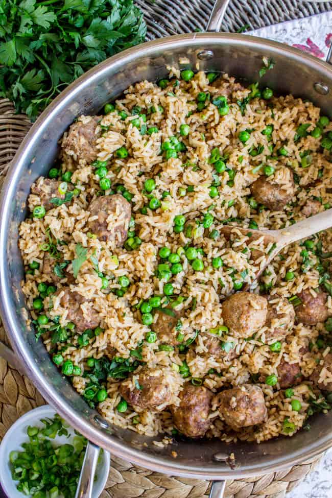 mixing rice, meatballs, and peas in a big metal skillet.