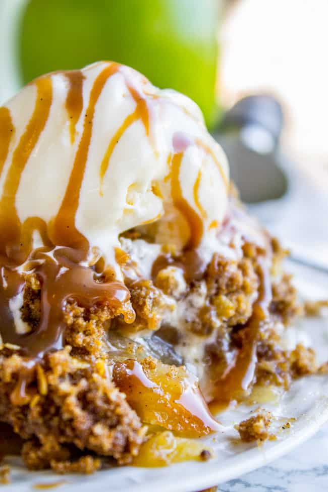 apple crisp topped with ice cream and caramel on a plate. 