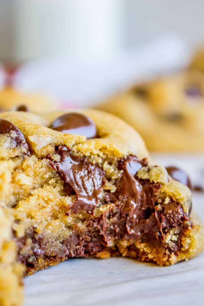 a chocolate chip cookie with melting chocolate chips and a big bite taken out of it. 