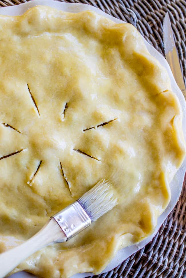 brushing a chicken pot pie with an egg wash. 