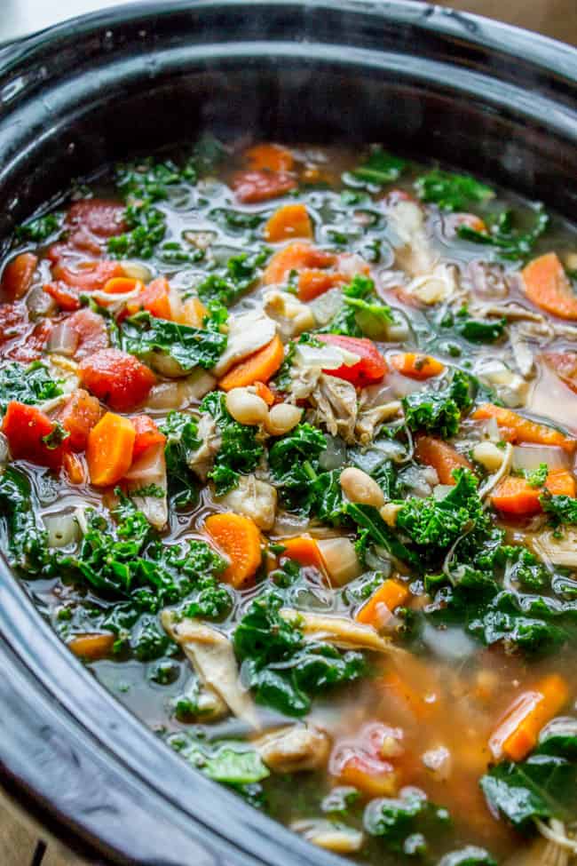 a slow cooker with chicken, kale, white bean, and parmesan soup.