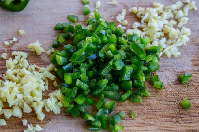 chopped garlic and jalapeno on a wooden cutting board. 