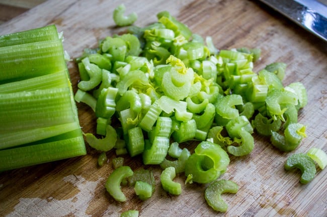 chopping celery on a wooden cutting board.