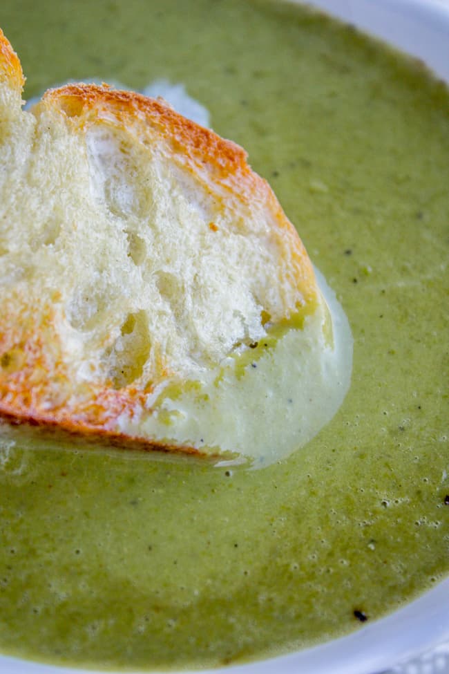 a baguette being dipped into homemade pea soup.