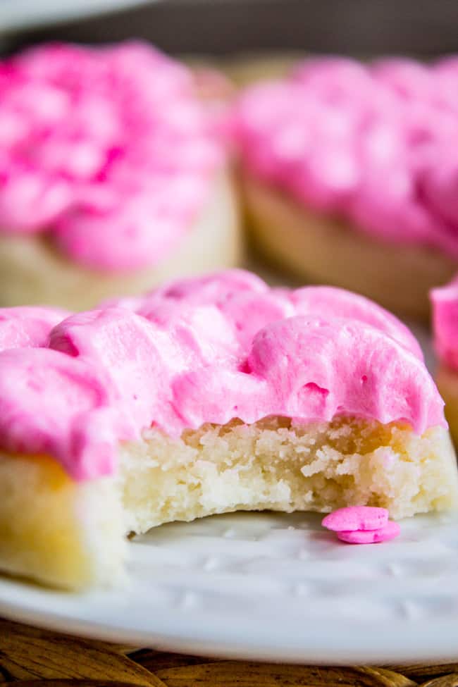 A soft sugar cookie topped with pink frosting with a bite taken out of it.