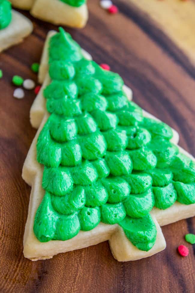 soft sugar cookie in shape of Christmas tree with dolluped green buttercream frosting