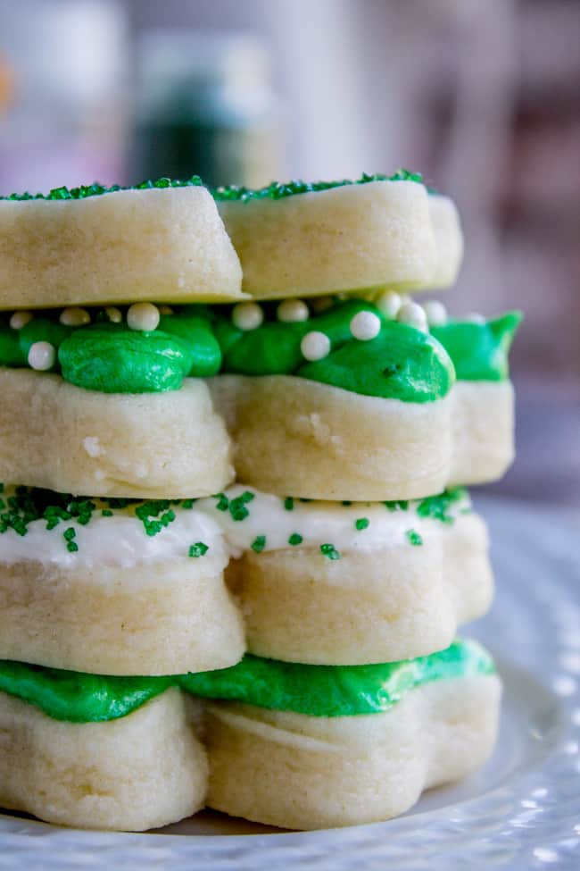 soft frosted sugar cookies stacked, frosted with green and white buttercream frosting and sprinkles