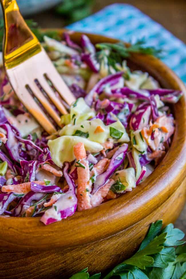 a wooden bowl of coleslaw with a fork.