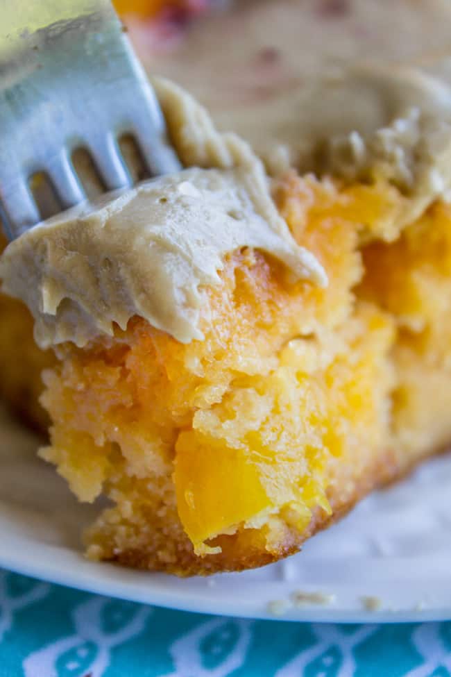 a slice of peach cake with brown sugar frosting with a fork in it.