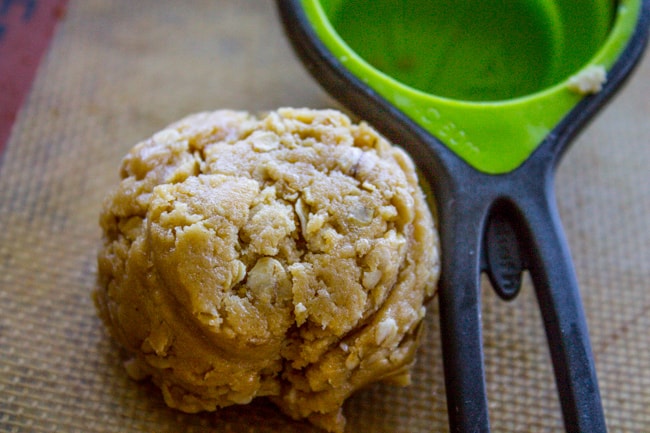 a 1/4 cup measuring cup with a ball of peanut butter oatmeal cookie dough.