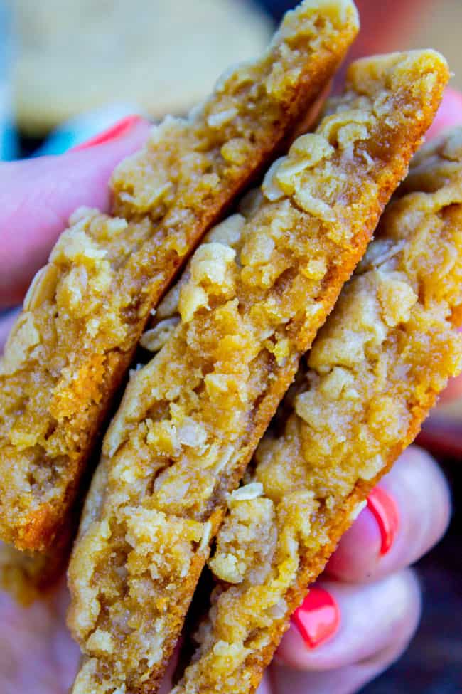 a hand holding a stack of peanut butter oatmeal cookies broken in half.