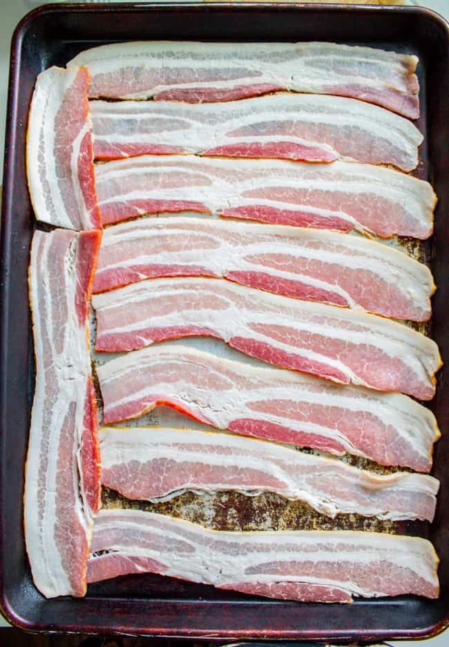 strips of raw bacon arranged on a sheet pan.