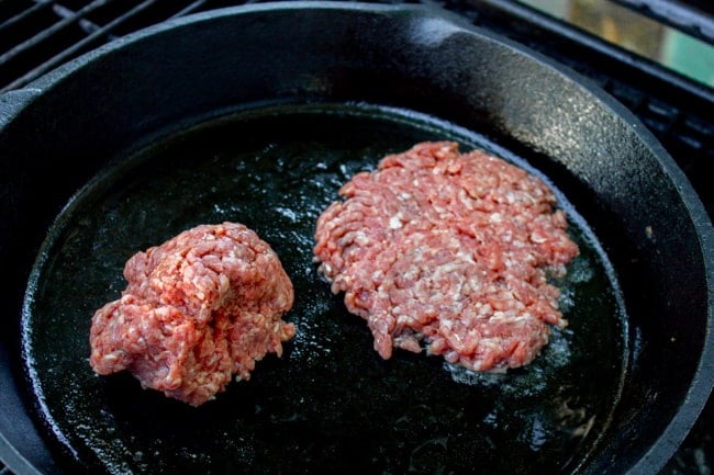 burgers about to be smashed in a cast iron skillet.