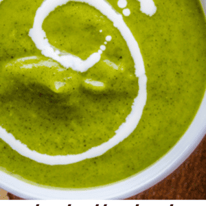 A bowl of creamy green zucchini soup with a swirl of white cream on top. Below the bowl, text reads: truly delicious creamy zucchini soup Ive ever had – The Food Charlatan.