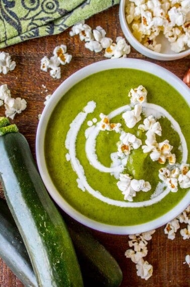 a bowl of zucchini soup topped with popcorn.