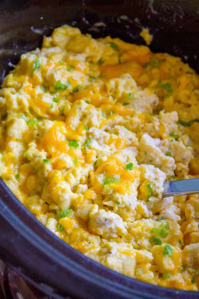 scrambled eggs in the crockpot with a metal spoon.