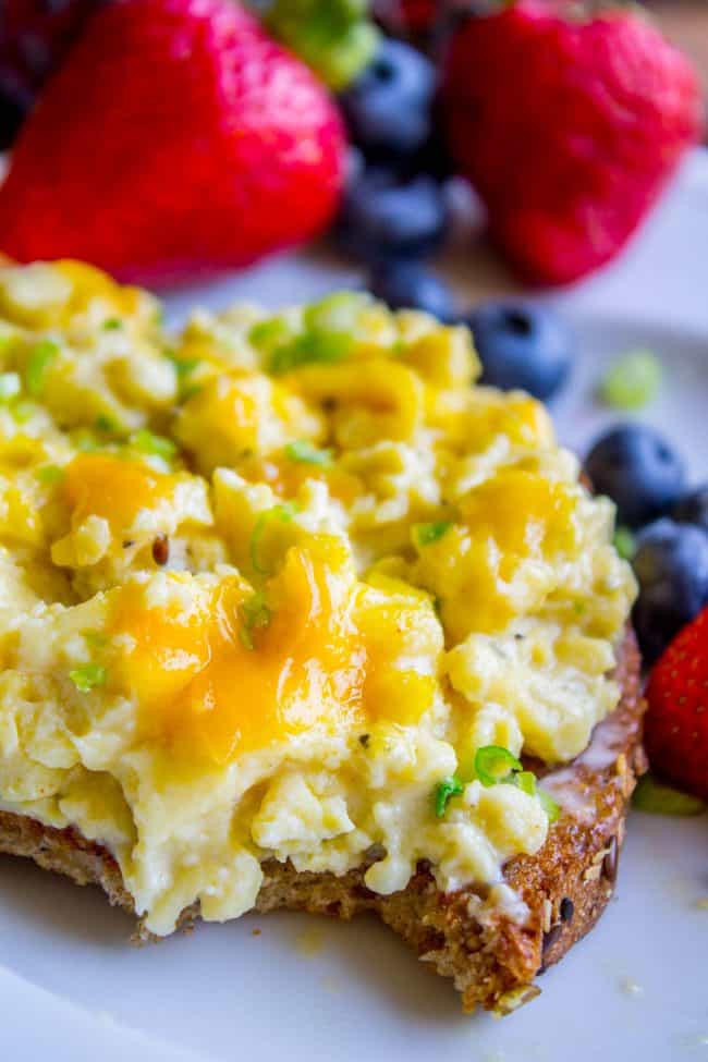 scrambled eggs piled on a piece of whole grain toast with fresh fruit.