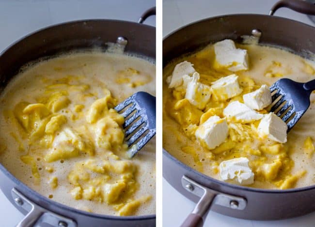 scrambled eggs slowly cooking in a pan, eggs in the pan with chunks of cream cheese added.