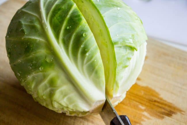 slicing a head of green cabbage in half.