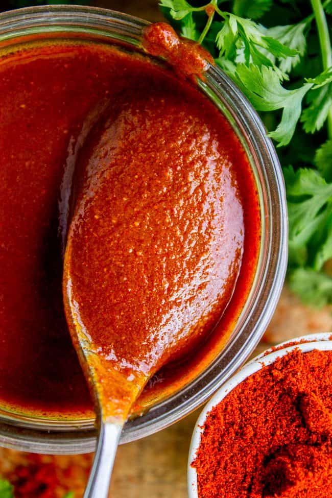 a jar of red enchilada sauce with parsley nearby. 