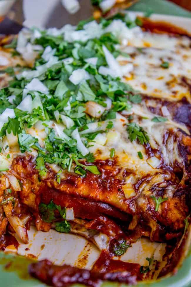 sweet potato and black bean enchiladas in a pan with a slice taken out.