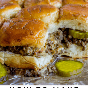 cheeseburger sliders on tinfoil with sliced pickles.