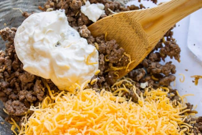Mixing filling of ground beef, mayo, and cheddar cheese.
