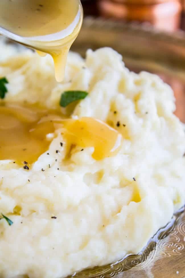 mashed potatoes with gravy being drizzled on top.