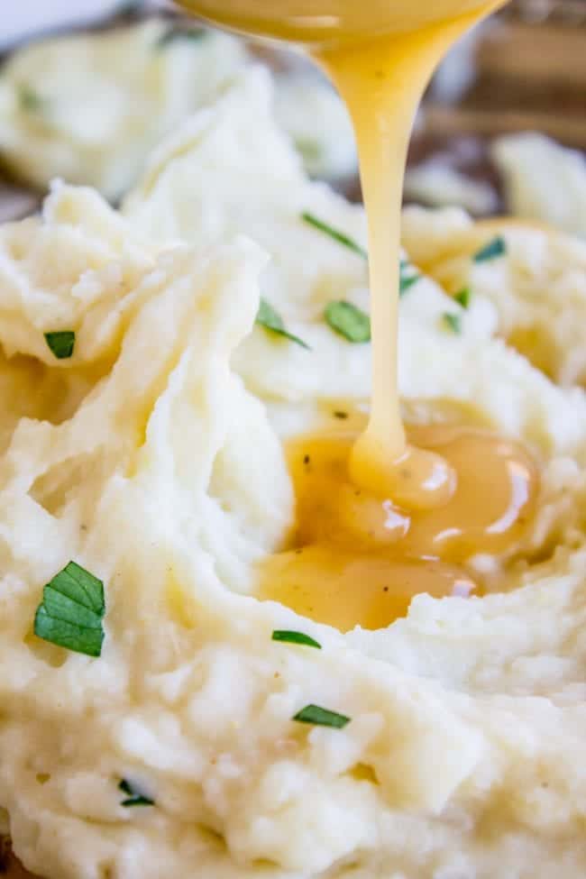 pouring gravy on creamy mashed potatoes.