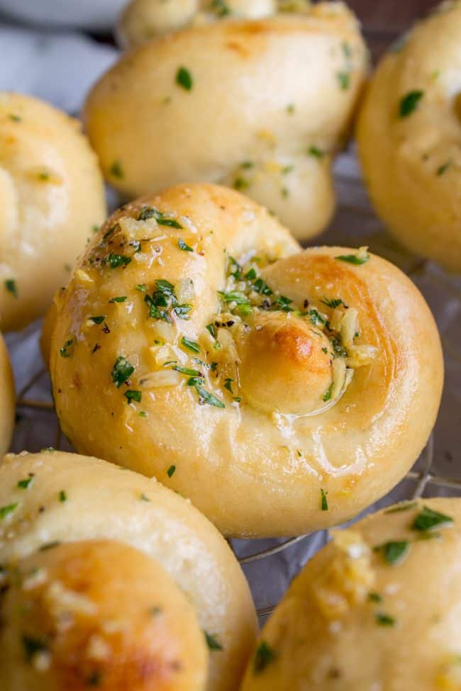 garlic knots with parsley garlic butter on a cooling rack.