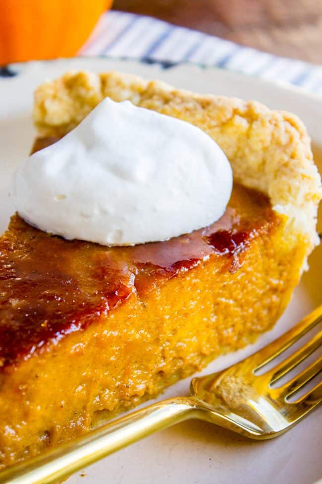 a slice of pumpkin pie with crackly creme brulee topping and fresh whipped cream. 