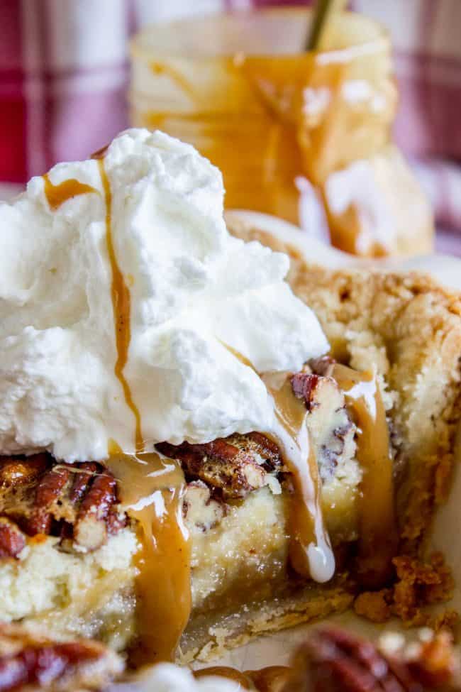 Slice of pecan pie cheesecake with whipped cream and caramel sauce.