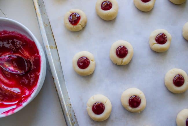 cookies laid out on baking sheet filled with raspberry jam.