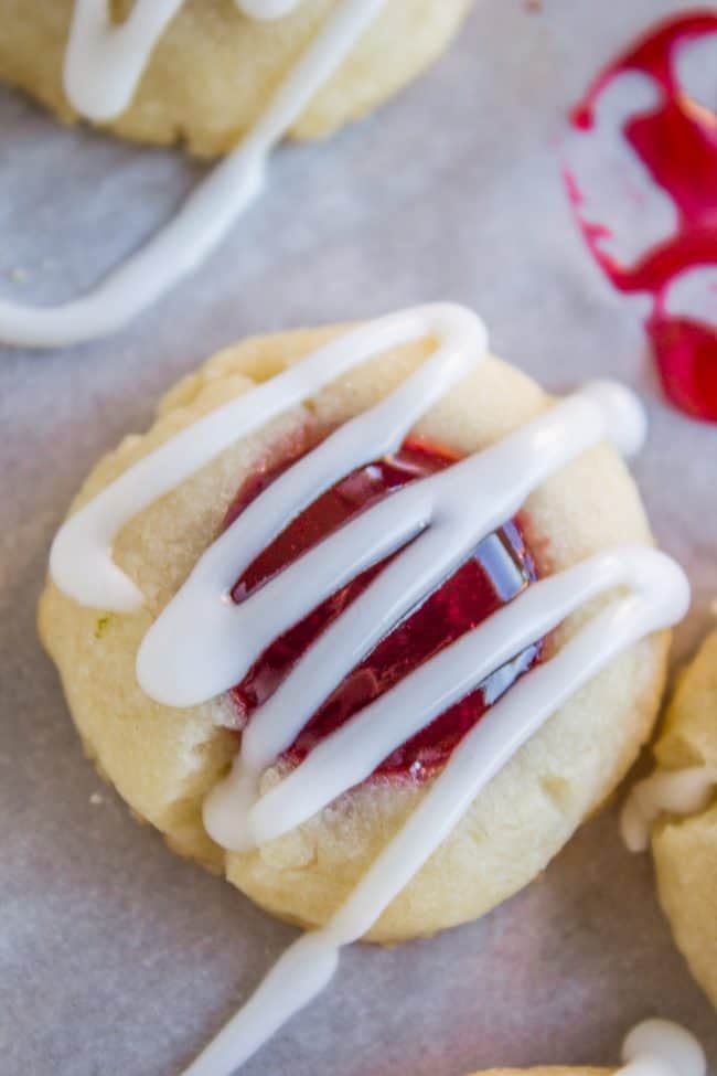 Raspberry Thumbprint Cookie with glaze on parchment paper.