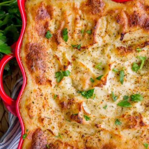 golden brown make ahead mashed potatoes in a red serving dish.