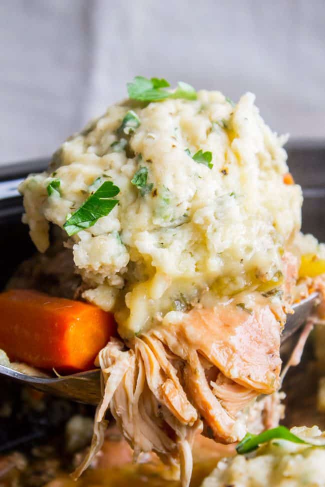 a metal spoon lifting shredded chicken, cooked carrots, and homemade dumplings. 