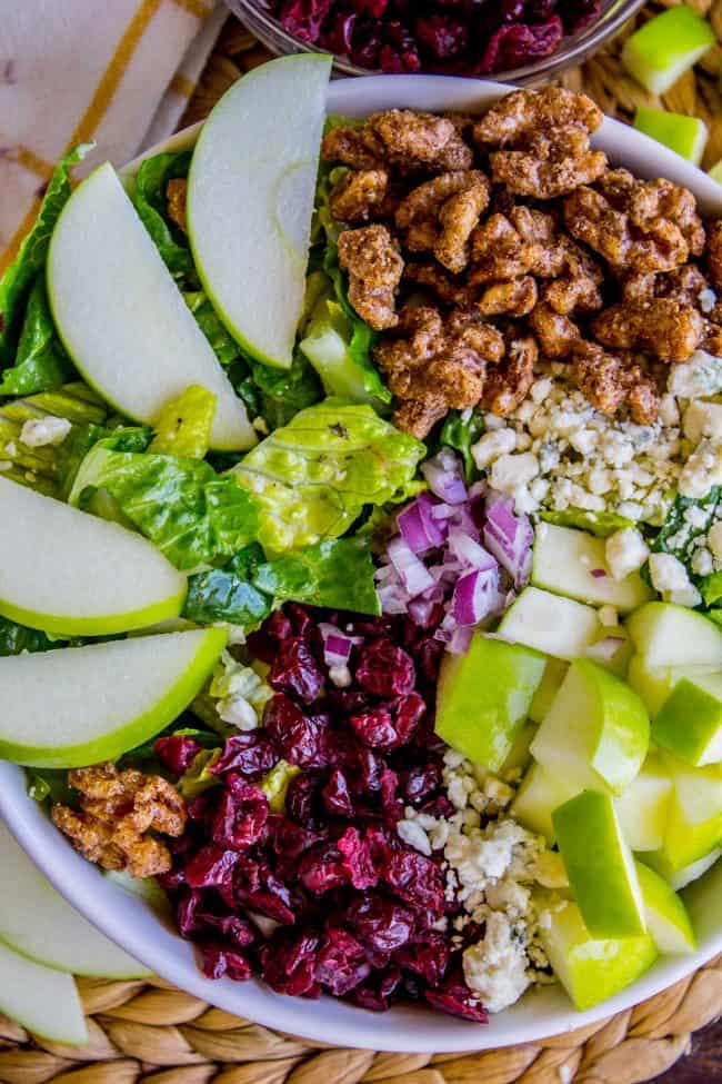 Apple Gorgonzola Salad features sliced green apples, candied walnuts, dried cranberries, chopped red onion, blue cheese crumbles, and crisp romaine lettuce in a vibrant bowl.