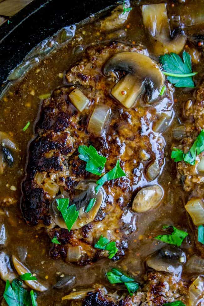 salisbury steak with mushroom gravy in a cast iron skillet.