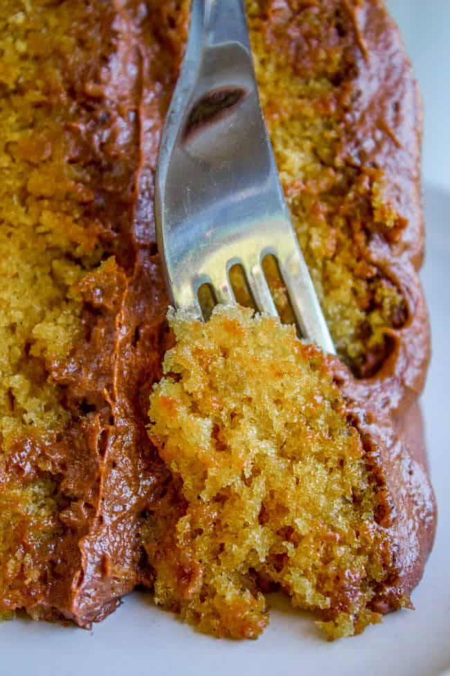 moist yellow cake with chocolate frosting and a fork.