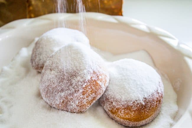 sugar cascading onto donuts in a bowl