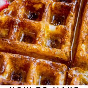 A close-up of golden brown waffles topped with syrup and butter, served with sliced strawberries and a fork in the background. Text at the bottom reads “Classic Waffles – The Food Charlatan.”.