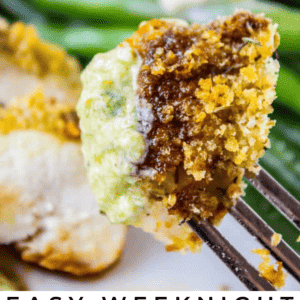 A fork holds a piece of baked chicken topped with pesto and a crispy breadcrumb coating. Green beans and more chicken are blurred in the background. Text on the image reads: Delicious Weeknight Baked Pesto Chicken.